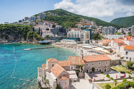 Foto de Una pequeña playa se sentó detrás de edificios medievales del casco antiguo de Budva en la costa de Montenegro visto en mayo de 2023. - Imagen libre de derechos