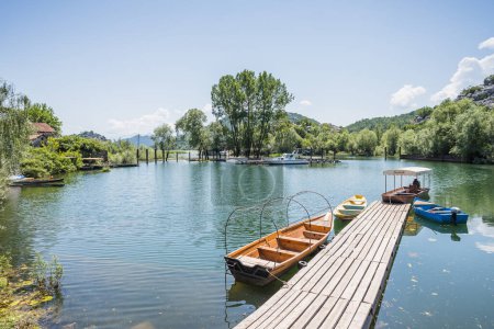 Foto de Barcos junto a una pasarela de madera en el pueblo de Karuc a orillas del lago Skadar en Montenegro, en mayo de 2023. - Imagen libre de derechos