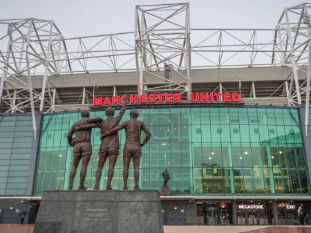 Foto de Estatua de la Trinidad Unida con las leyendas del Manchester United George Best, Denis Law y Sir Bobby Charlton fotografiados frente al estadio Old Trafford y la estatua de Sir Matt Busby en Manchester el 2 de enero de 2024. - Imagen libre de derechos