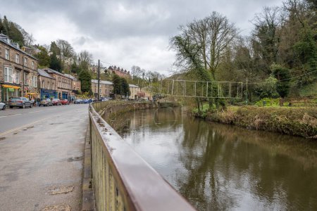 La promenade commerciale le long de Matlock Bath dans le Derbyshire rencontre la rivière Derwent et le parc en face illustré en avril 2024.