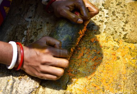 Téléchargez les photos : Une femme broyant du curcuma à l'aide d'un instrument rocheux pour faire de la médecine ayurvédique ou à base de plantes. Concentration sélective. - en image libre de droit