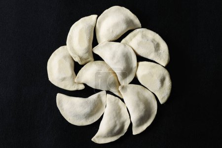 Photo for Raw dumplings made by hand on a black background. - Royalty Free Image