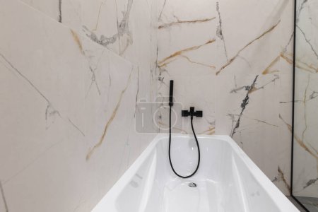 Téléchargez les photos : White acrylic bathtub in a modern interior of a new apartment - en image libre de droit
