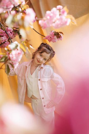 Photo for A girl in a good mood on a beige background and a branch of blooming sakura. - Royalty Free Image