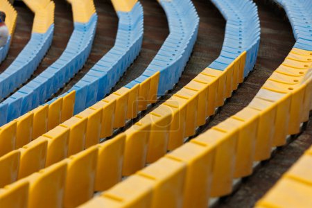 Téléchargez les photos : Sièges bleus et jaunes autour du terrain de football du stade ukrainien. Sièges pour ventilateurs - en image libre de droit