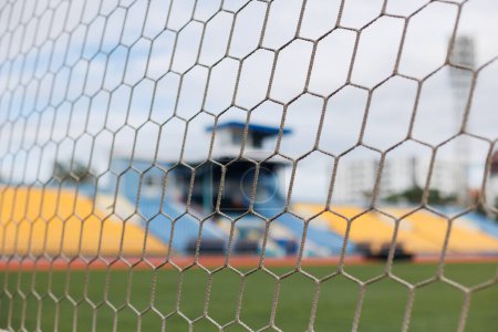 Téléchargez les photos : Gros plan du filet de but de football dans le stade contre la zone des supporters bleu et jaune - en image libre de droit