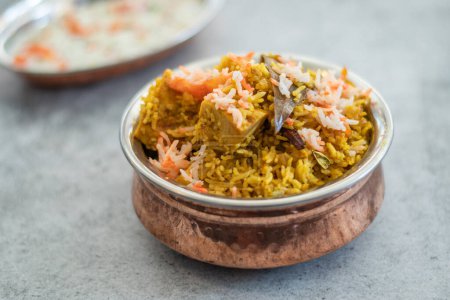 Pulao biryani indio picante en tazón de oro con plato de arroz basmati de la India con pollo al curry de carne Ramadan Kareem, Eid. Cuenco de latón con fondo blanco, Copyspace.