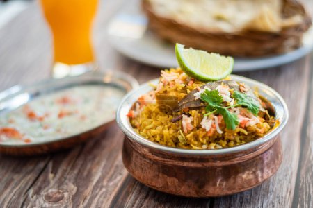 Spicy Indian biryani pulao in golden bowl with India basmati rice dish with chicken meat curry Ramadan Kareem, Eid. Brass serving bowl with white background, Copyspace.