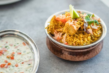 Pulao biryani indio picante en tazón de oro con plato de arroz basmati de la India con pollo al curry de carne Ramadan Kareem, Eid. Cuenco de latón con fondo blanco, Copyspace.