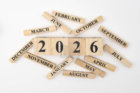 Wooden blocks and cubes with the year 2026 and the 12 months of the year randomly scattered around. Isolated on white background.