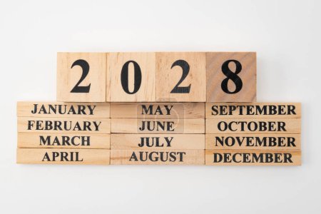 Jahr 2028 geschrieben auf Holzwürfeln über den Monaten des Jahres geschrieben auf zwölf rechteckigen Holzstücken. Isoliert auf weißem Hintergrund.