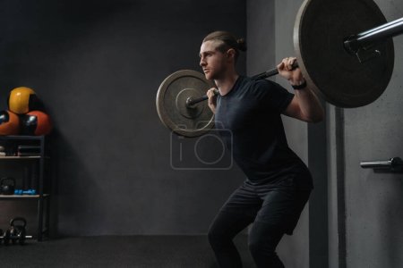 Photo for Crossfit athlete lifting barbell in dark workout gym. Functional and circuit training concept. Copy space - Royalty Free Image