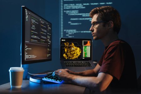 Foto de Profile view portrait of young guy data scientist working at pc at home late night, debugging script cyber space error, isolated on wall with zoomed digital page - Imagen libre de derechos