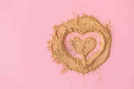 Photo for Top view of heart shape made of raw maca root powder on soft pink background with copy space - Royalty Free Image