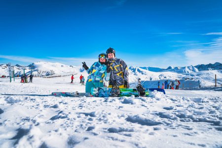 Foto de Pareja, esquiador y snowboarder sentado en la nieve y mirando a la cámara, Pirineos Montañas. Vacaciones de esquí de invierno en El Tarter, Grandvalira Andorra - Imagen libre de derechos