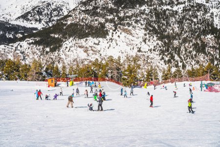 Foto de People, families and kids having fun and learning how to ski and snowboard on El Tarter green slops. Winter ski holidays in Andorra Pyrenees Mountains - Imagen libre de derechos