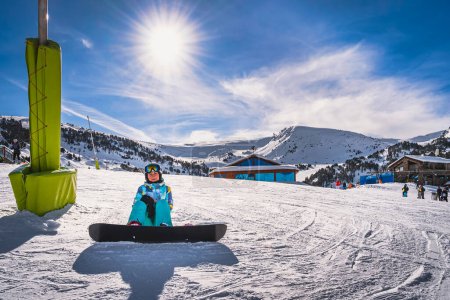 Foto de Portrait of a woman snowboarder sitting on snow and looking at camera. Winter ski holidays in El Tarter, Grandvalira, Andorra, Pyrenees Mountains - Imagen libre de derechos