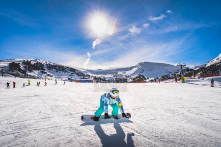 Foto de Woman, falling down when learning how to ride on a snowboard. Winter ski holidays in El Tarter, Grandvalira, Andorra, Pyrenees Mountains - Imagen libre de derechos