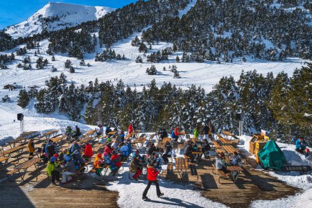 Foto de El Tarter, Andorra, Jan 2020 People sitting at the tables relaxing and eating with a beautiful view on snowy mountains and forest. Winter ski holidays - Imagen libre de derechos