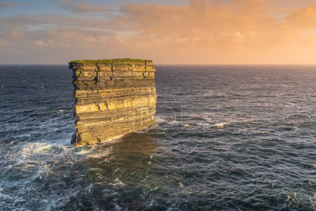 Téléchargez les photos : Downpatrick Pile marine de tête éclairée par le lever du soleil, avec des couches rocheuses de millénaires d'érosion debout dans l'océan Atlantique. Wild Atlantic Way Mayo Irlande - en image libre de droit