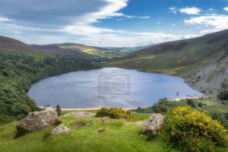 Photo for View on Lough Tay, called Guiness Lake with moored Viking longships and wooden village in Wicklow Mountains, Ireland - Royalty Free Image