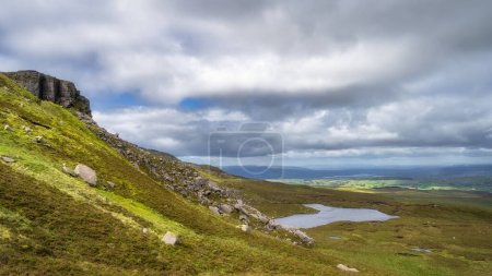 Cuilcagh Mountain Park mit Blick auf Klippen, Felsrutschen und Rumpeln, die hinunter zu einem kleinen See führen, der von Sümpfen und Feuchtgebieten umgeben ist Fermanagh, Nordirland
