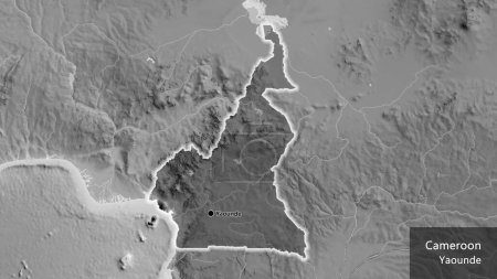 Téléchargez les photos : Gros plan de la frontière camerounaise en surbrillance avec une superposition sombre sur une carte en niveaux de gris. Point capital. Briller autour de la forme du pays. Nom anglais du pays et de sa capitale - en image libre de droit