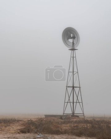 Foto de Molino de viento solitario en la llanura en una mañana de fogy de Texas - Imagen libre de derechos