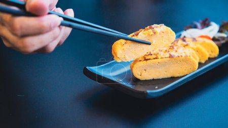Photo for Chopstick hold Tamagoyaki, Soft focus sweet omelette in Japanese - Royalty Free Image