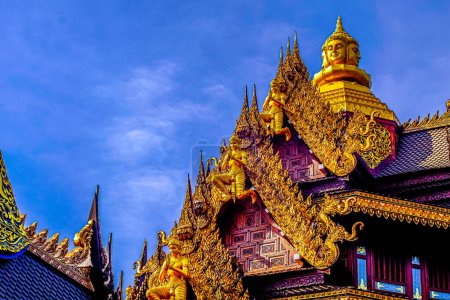 Foto de Dioses animales tradicionales de estilo tailandés tallados en las decoraciones del techo contra un cielo azul - Imagen libre de derechos