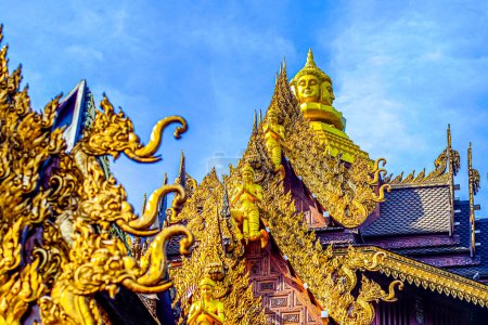 Photo for Traditional Thai Style Animal Gods Carved on Roof Decorations Against a Blue Sky - Royalty Free Image