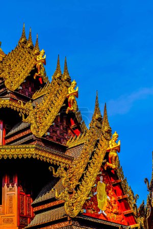 Foto de Dioses animales tradicionales de estilo tailandés tallados en las decoraciones del techo contra un cielo azul - Imagen libre de derechos