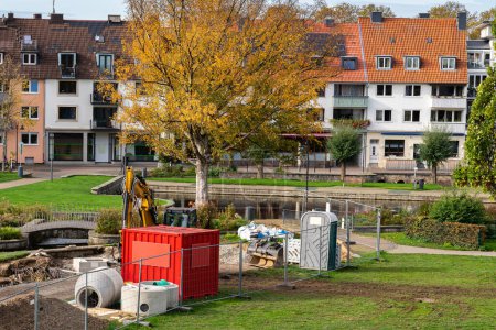 Foto de Sitio de construcción con excavadoras y contenedores de metal rojo en la zona de aparcamiento de la zona residencial. - Imagen libre de derechos