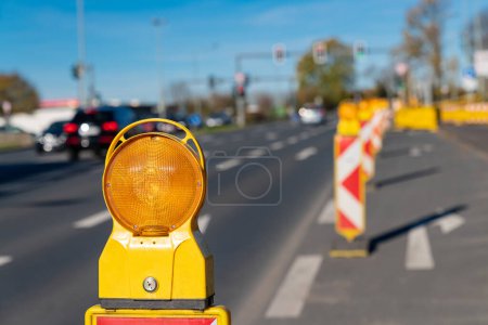 Photo for Orange signal lamp on the carriageway of the highway enclosing the construction site. Selective focus. Close up. - Royalty Free Image