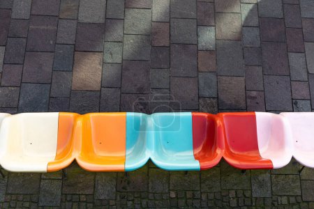 Photo for Bright multi-colored plastic seats against a gray sidewalk. View from above. - Royalty Free Image