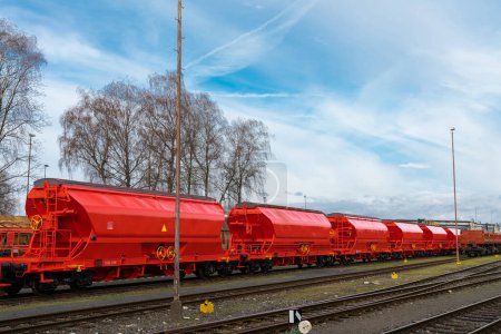 Bright red railway tanks stand on the sidings. Blue sky with light clouds.