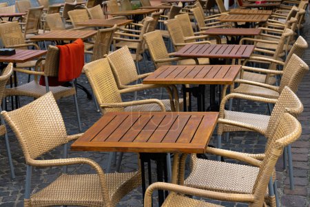 Photo for Free wooden tables and wicker chairs standing in rows near the summer cafe. - Royalty Free Image