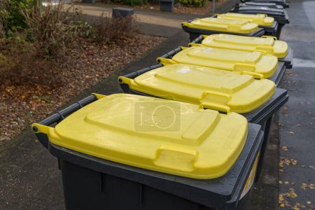 Foto de Tapas amarillas de botes de basura de plástico de pie a un lado de la carretera. - Imagen libre de derechos