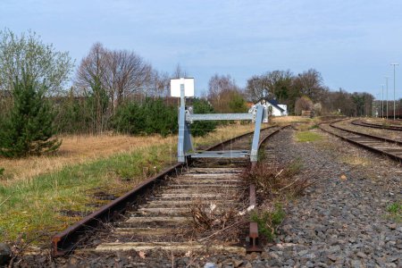 A dead end on old railway tracks is protected by a warning metal barrier.