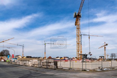 Start of construction of a concrete residential building. Construction cranes against a cloudy sky.