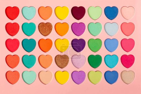 Foto de Palette of eyeshadows with multicolor heart-shaped refilles close up. Eyeshadows in macro. Cosmetic brush - Imagen libre de derechos