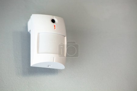 Téléchargez les photos : Une caméra de détection de mouvement blanche sur un mur gris, offrant sécurité et surveillance - en image libre de droit