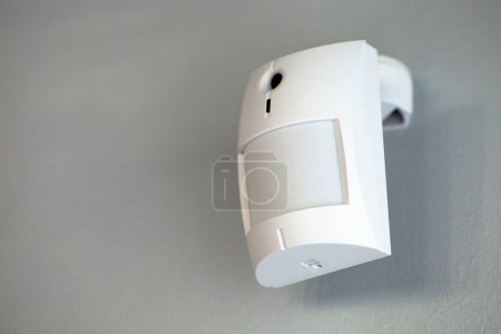 Téléchargez les photos : Une caméra de détection de mouvement blanche sur un mur gris, offrant sécurité et surveillance - en image libre de droit
