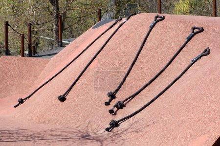 Cuerdas de escalada para juegos infantiles con asas bajo luz solar brillante en una estructura de juego al aire libre