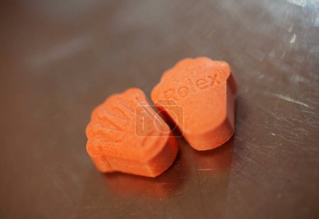 Orange pills with mdma ecstasy dope rolex drug close up background fine art in high quality prints Poster 632642312
