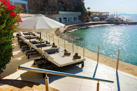 Photo for Ses Illetes, Majorca, Balearic islands, Spain. July 20th, 2022 - Terrace of the Purobeach beach club spa in Bendinat public cove, with umbrellas and loungers - Royalty Free Image