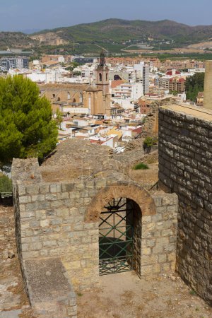 Photo for Sagunto, Valencia, Spain. August 30th, 2022 - View of the city, the old town, the church of Holy Mary, from a viewpoint next to a door of the roman theatre - Royalty Free Image