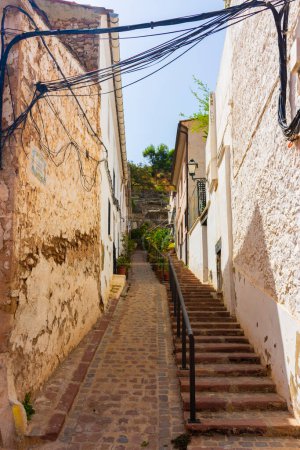 Photo for Sagunto, Valencia, Spain. August 30th, 2022 - Old street with stairs, in the Jewish quarter of the city, towards the slope of the mountain where the castle is located - Royalty Free Image