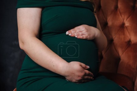 Foto de Embarazada chica en un vestido sostiene sus manos en su vientre - Imagen libre de derechos