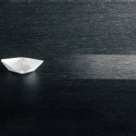 White Paper Boat Following Arrow Icon On Modern Black Wooden Table Leading A Fleet Of Small Boats - Leadership Concept